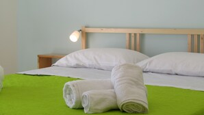 A neatly made bed with white linens and a green bedspread, a wooden headboard, and a bedside lamp. - Mary Holidays House (Ragusa)