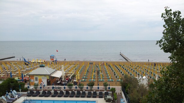 Un hôtel situé en bord de mer, doté d’une piscine, de chaises longues et offrant une vue sur l’océan.