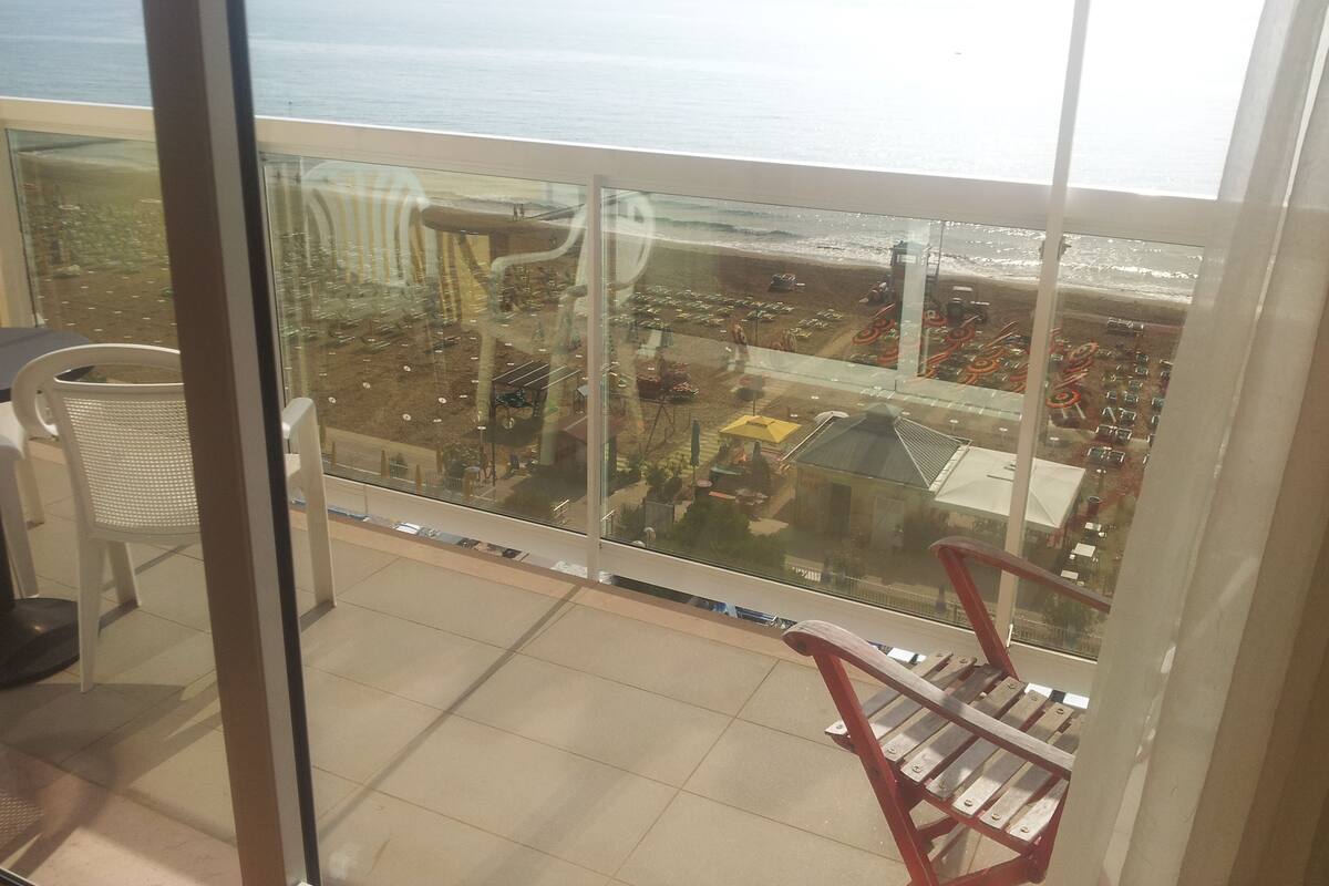 A balcony with a view of a beach and a parking area.