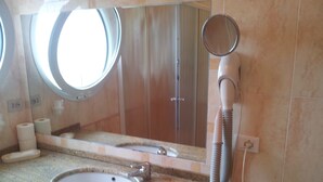 Une salle de bain équipée d’un lavabo, d’un miroir et d’un sèche-cheveux.