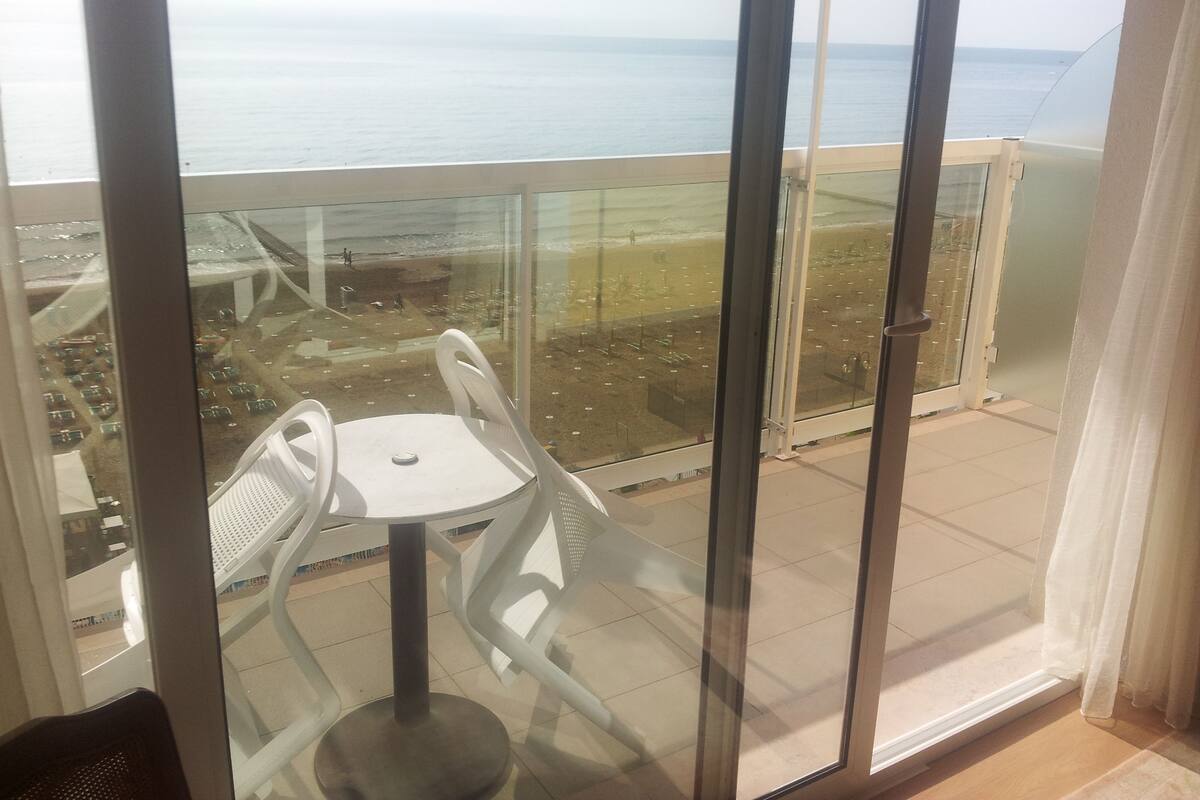 A balcony with a glass door, a white table, and two white chairs.