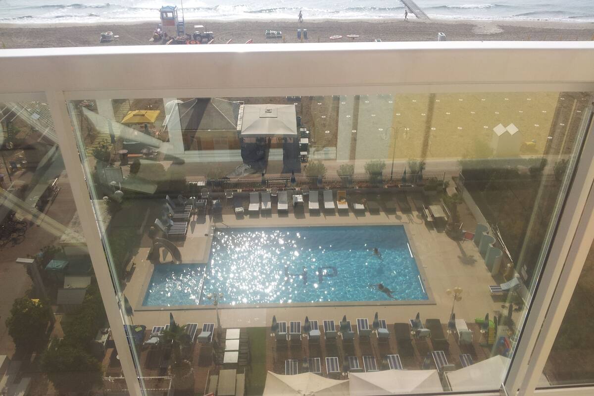A pool area with lounge chairs and umbrellas, a view of the beach, and a lifeguard tower.