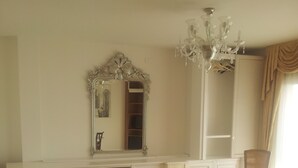 Une chambre à coucher avec un grand lit, une coiffeuse avec un miroir, un lustre et une chaise.