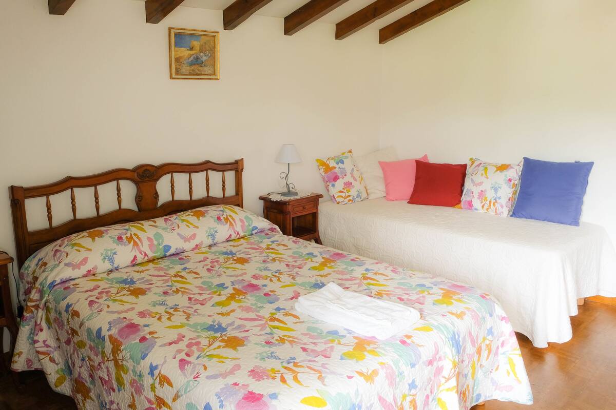 A bedroom with a wooden bed, a nightstand with a lamp, and a painting on the wall.