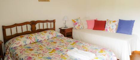 Un dormitorio con una cama de madera, una mesita de noche con lámpara y un cuadro en la pared.