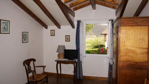 A room with a wooden ceiling, a desk with a lamp, a chair, and a window with curtains. - Chambres D'Hôtes Garicoitz (Saint-Jean-Pied-de-Port)