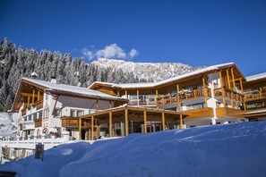 Ein mehrstöckiges Hotel mit hölzernen Balkonen und einer Bergkulisse.