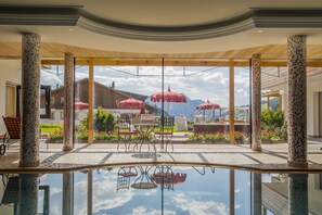 Ein überdachter Außenbereich mit Pool, roten Sonnenschirmen und Gartenmöbeln.