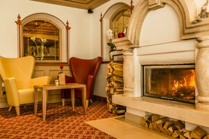 Una habitación acogedora con chimenea, un sillón amarillo, un sillón rojo y una mesa de madera.