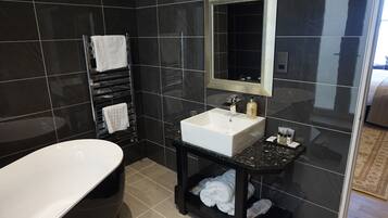 Un baño moderno con una bañera independiente, un tocador con espejo y un perchero para toallas.