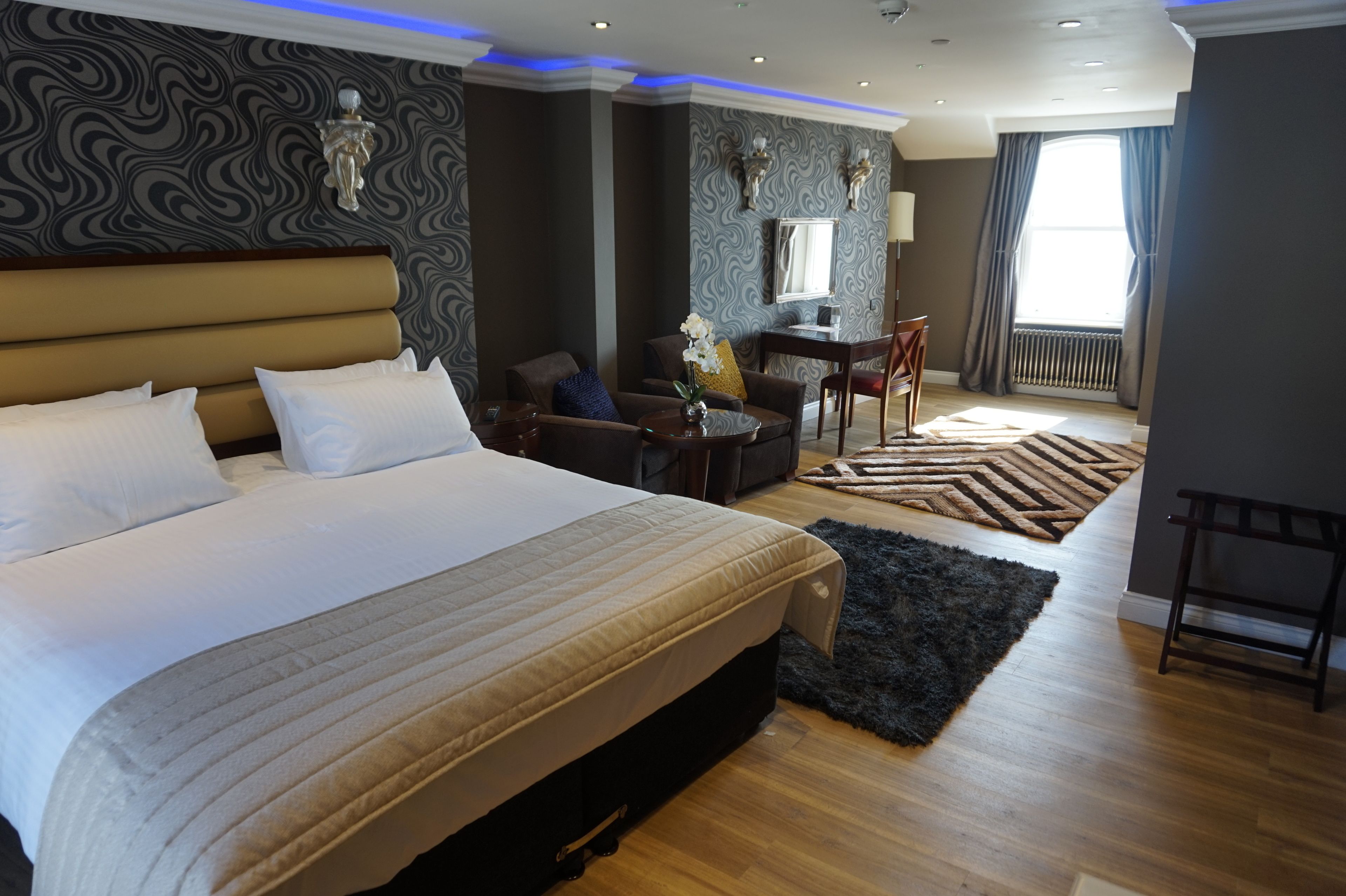 Ein modernes Hotelzimmer mit einem großen Bett, einem Schreibtisch und einem Sessel.