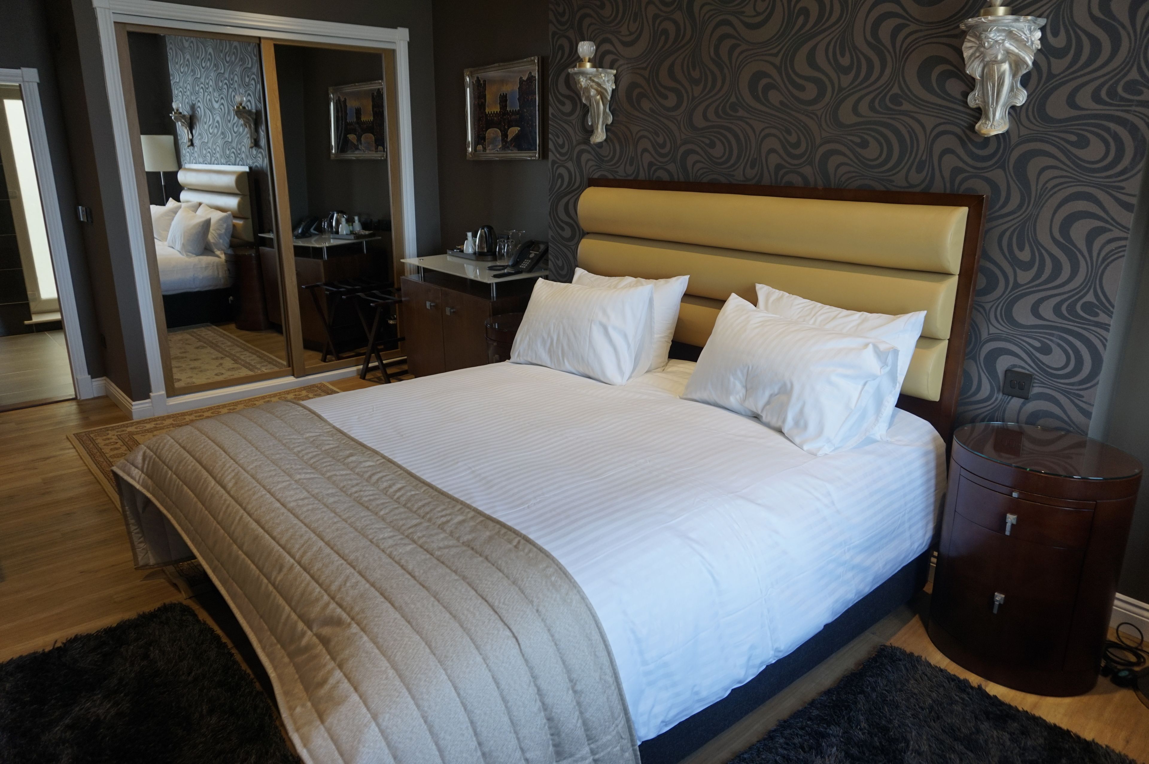 A neatly made bed with a headboard, a bedside table, and a small cabinet.