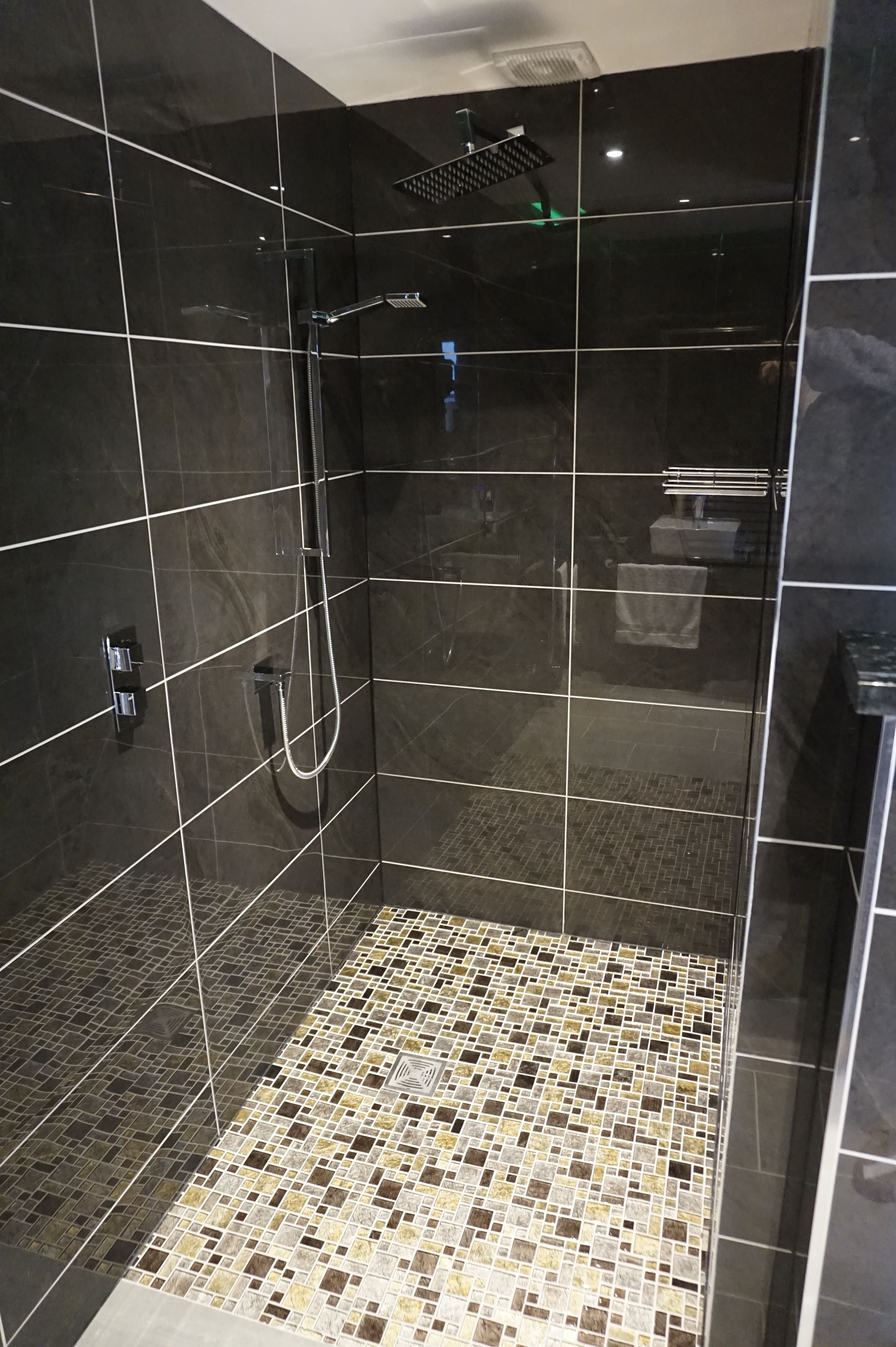 A shower with a glass door, a tiled floor, and a showerhead.