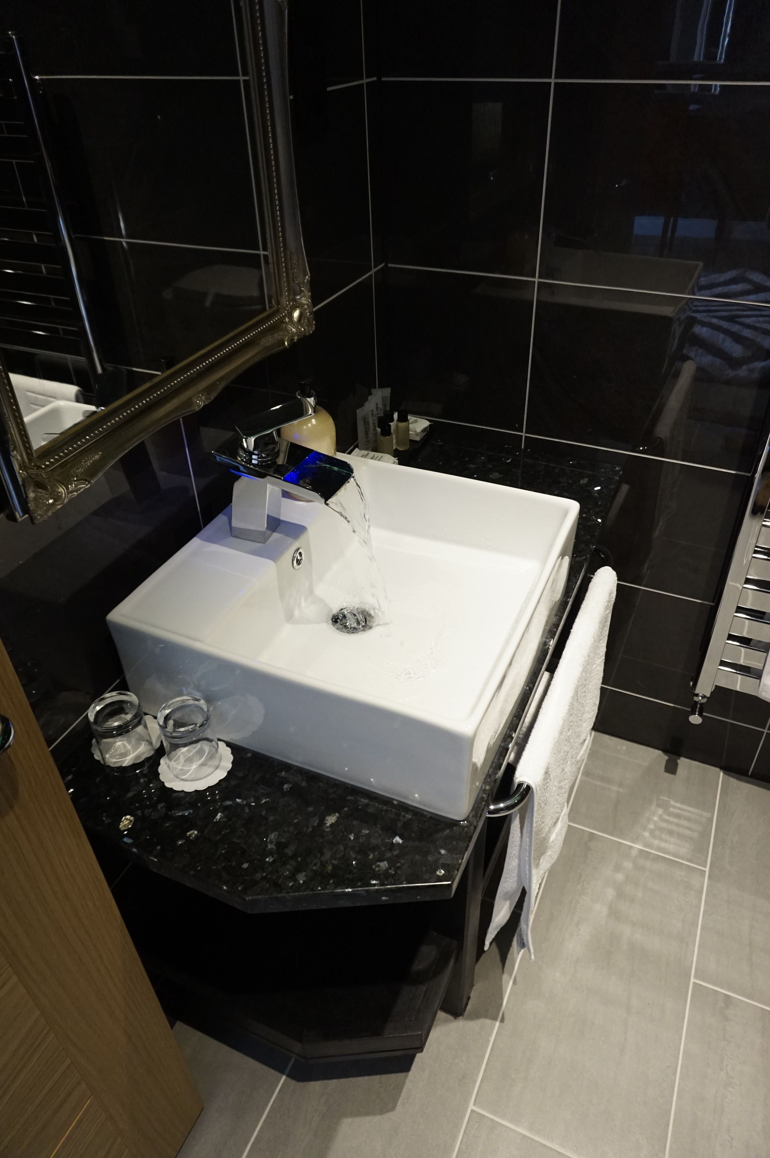 A modern bathroom with a white sink, black countertop, and a mirror above the sink.