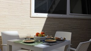 Une table à manger avec des chaises, un saladier de fruits, des assiettes et des verres.