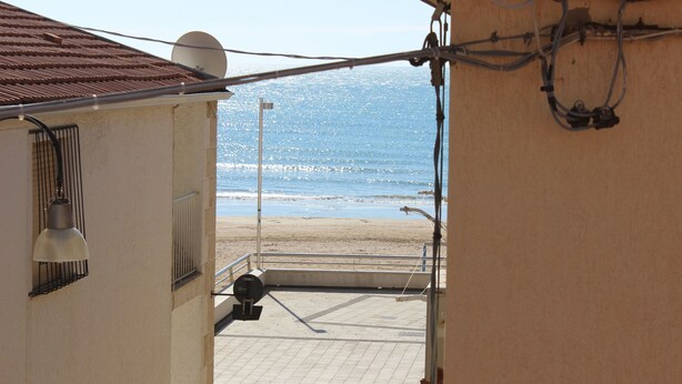 Une vue depuis un balcon donnant sur une plage, avec un sol carrelé et une balustrade.