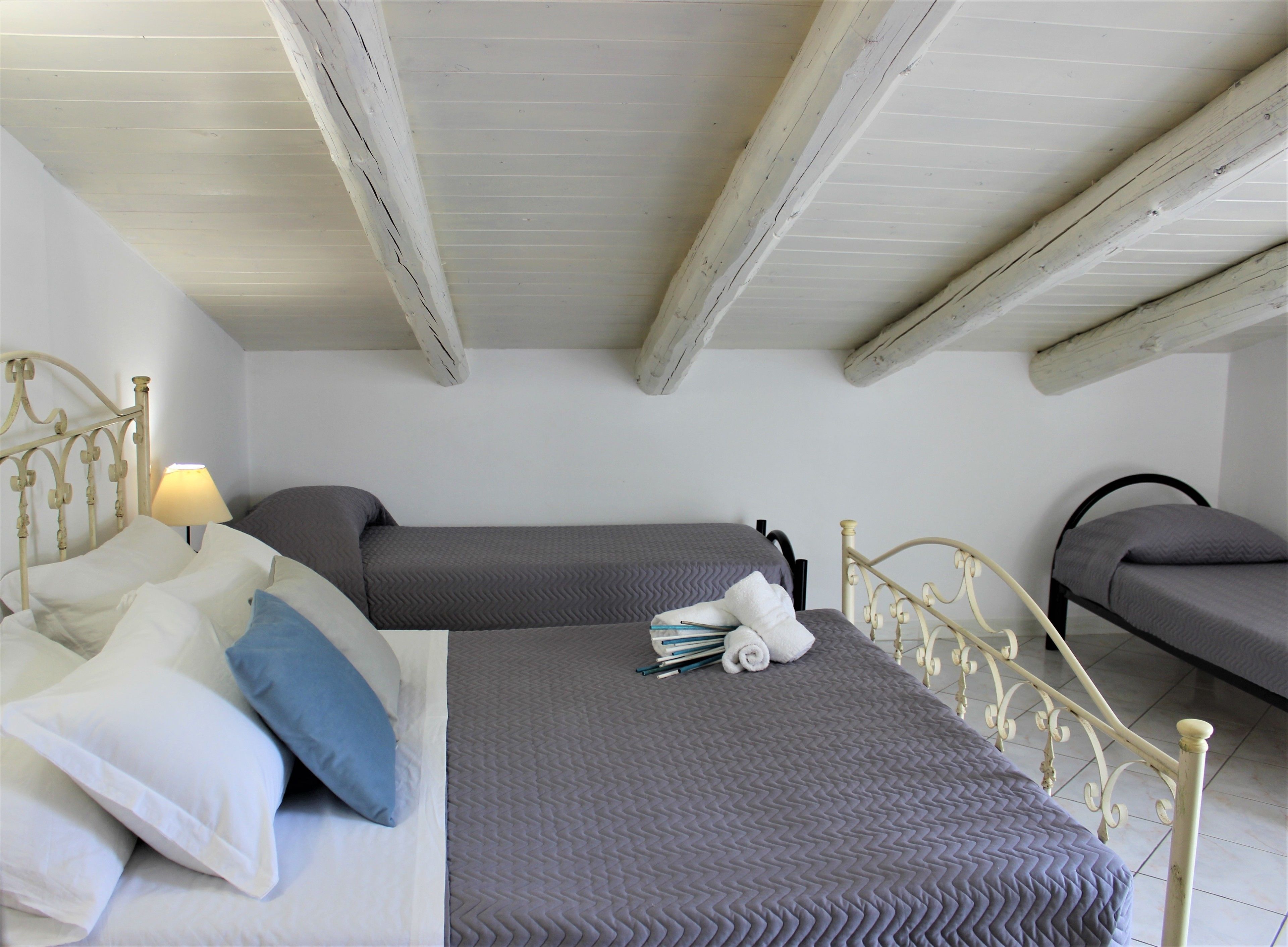 A bedroom with two beds, a nightstand, and a lamp.