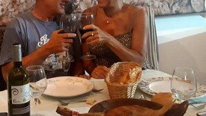 Una mesa de comedor con platos, vasos, una botella de vino y una cesta de pan.
