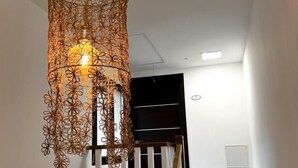 Una escalera con barandilla blanca y una lámpara colgante con motivos florales.