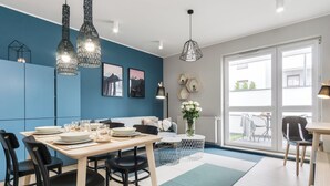 Un espace de salle à manger moderne avec une table en bois pour quatre personnes, des chaises noires et un mur d’accent bleu.