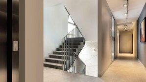 Un intérieur moderne avec un escalier, un couloir et une porte.
