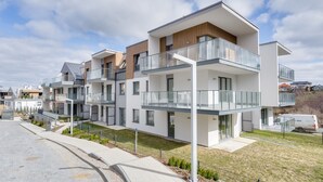 Un immeuble résidentiel moderne doté de nombreux balcons, d’une allée pavée et d’un espace verdoyant.