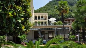 Un hotel con balcón, mobiliario exterior y abundante vegetación.