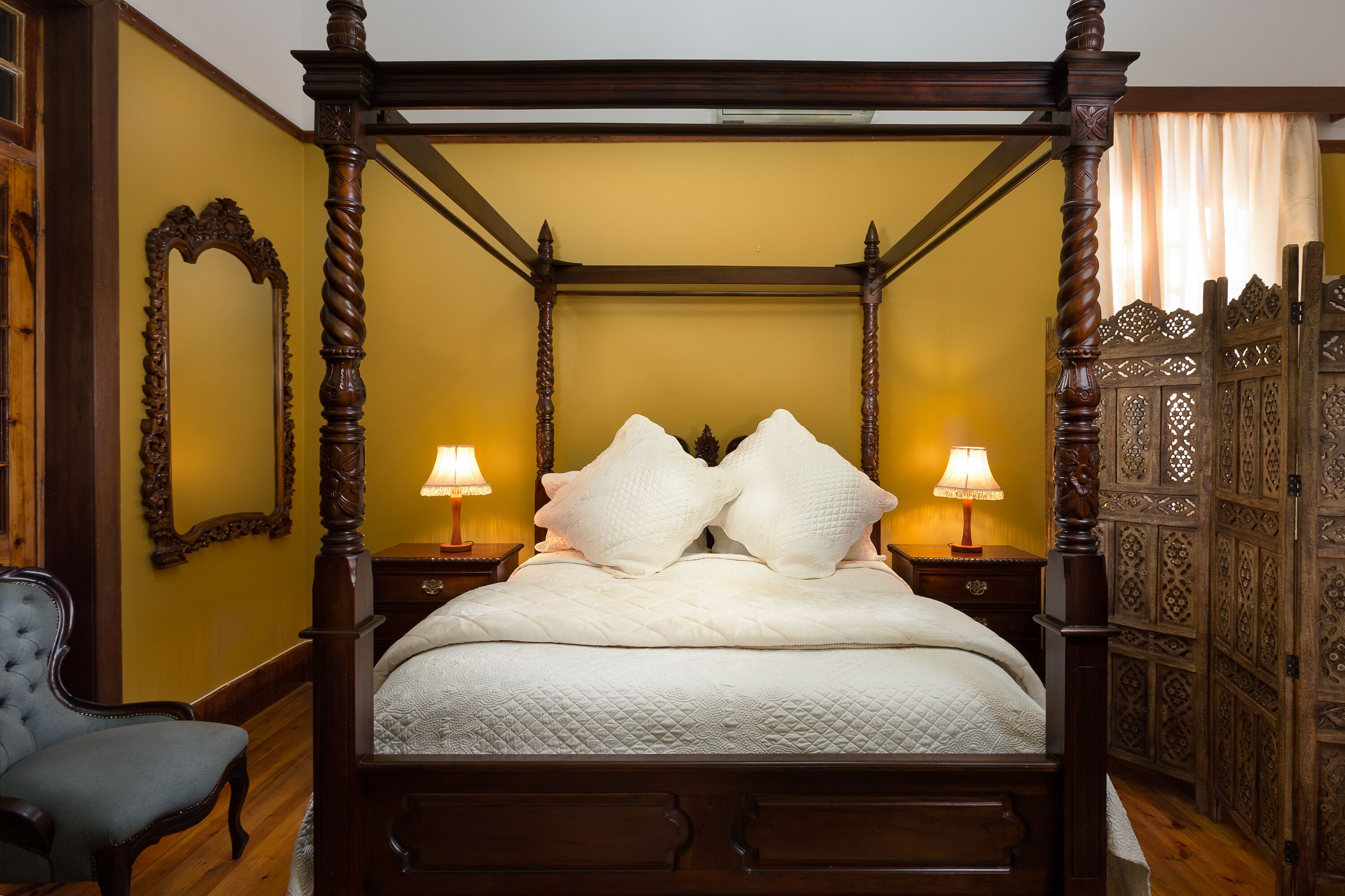 Una cama con dosel y dos lámparas a cada lado, con un edredón acolchado.