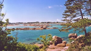 A coastal landscape with clear turquoise waters, rocky formations, and dense greenery. - Hôtel Restaurant La Maison (Trébeurden)