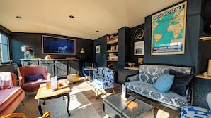 A modern living room with a sofa, armchairs, a coffee table, and a bookshelf. - Hôtel Restaurant La Maison (Trébeurden)