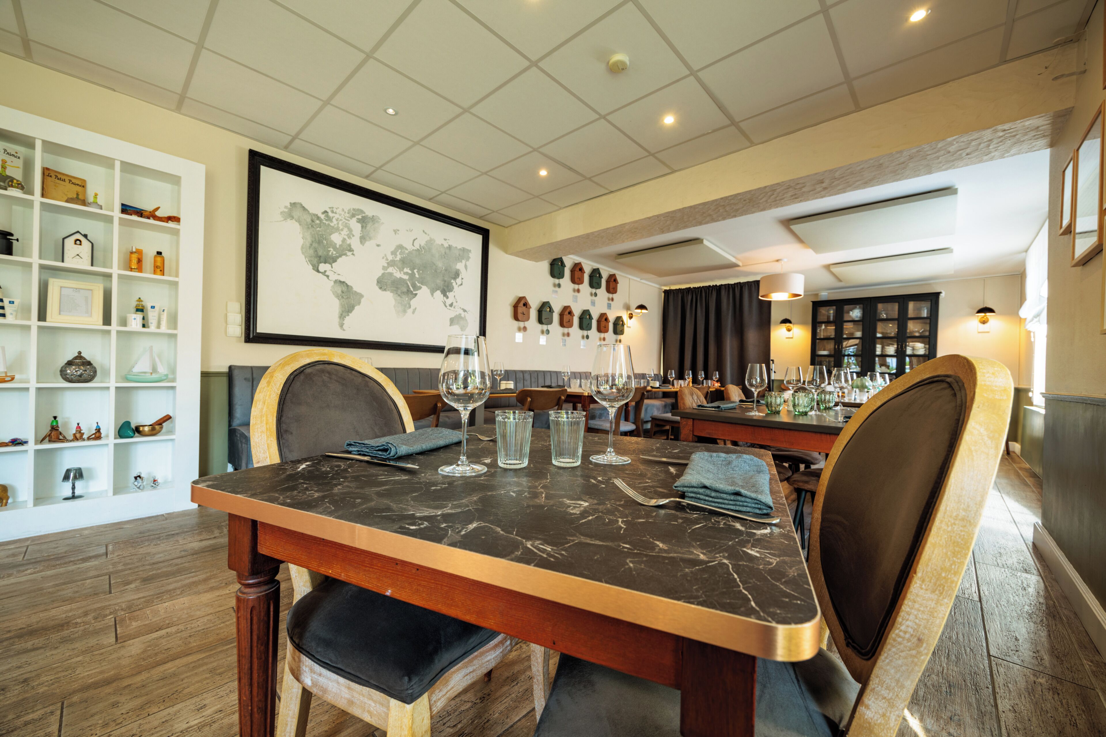 Un comedor con una mesa de mármol, sillas y un mapa mundial en la pared.