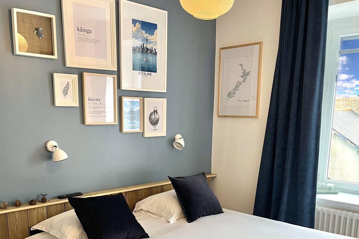 A neatly arranged hotel room with a large bed, framed artwork on the walls, and a window with curtains.
