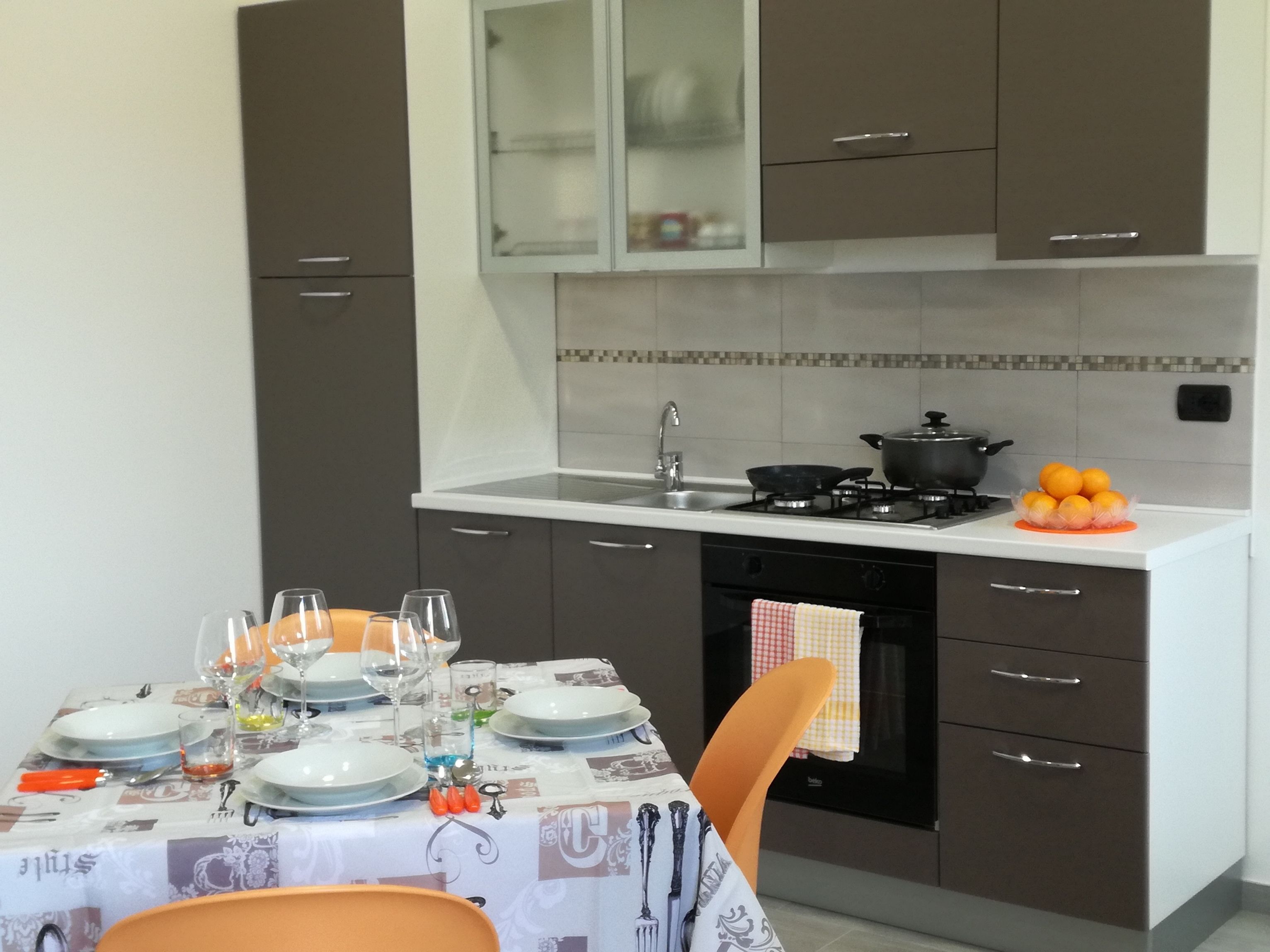 A modern kitchen with a dining table set for four, a stove, and a sink.