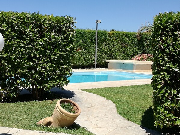 A swimming pool surrounded by well-maintained hedges and a stone pathway. - La Lantana (Ragusa)