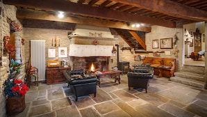 A rustic living room with stone walls, a fireplace, leather sofas, and a wooden staircase. - Agriturismo Castello della Pieve (Mercatello sul Metauro)
