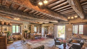 A rustic stone-floored room with exposed wooden beams, stone walls, and traditional furnishings including leather sofas and a dining table. - Agriturismo Castello della Pieve (Mercatello sul Metauro)