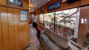 Un restaurante con paredes de madera, suelo con estampado de espiga y un amplio ventanal con plantas en macetas.