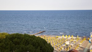 Una playa con sombrillas amarillas y tumbonas, un muelle y una vista despejada del mar.
