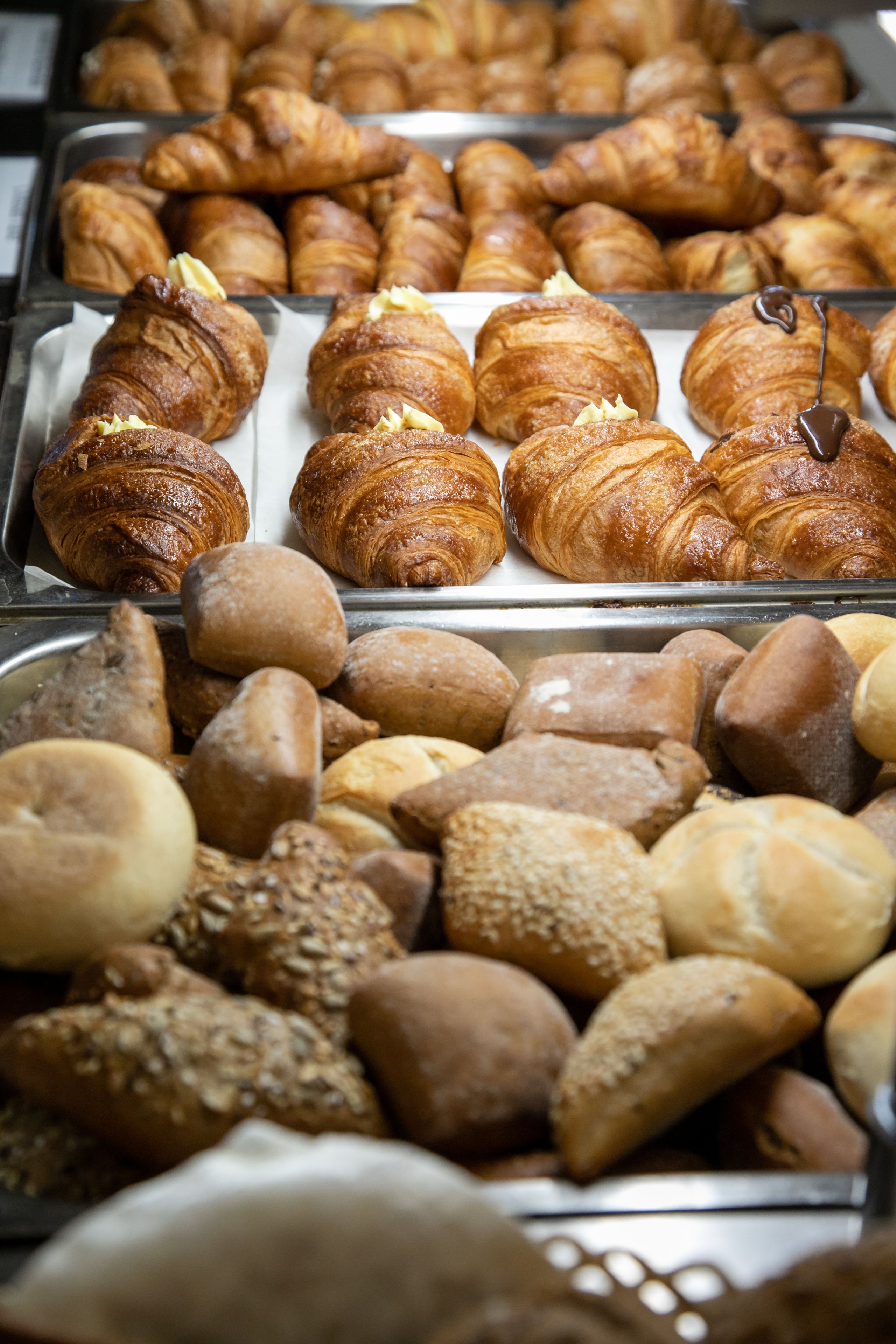 A variety of baked goods including croissants and bread, displayed in a bakery setting.