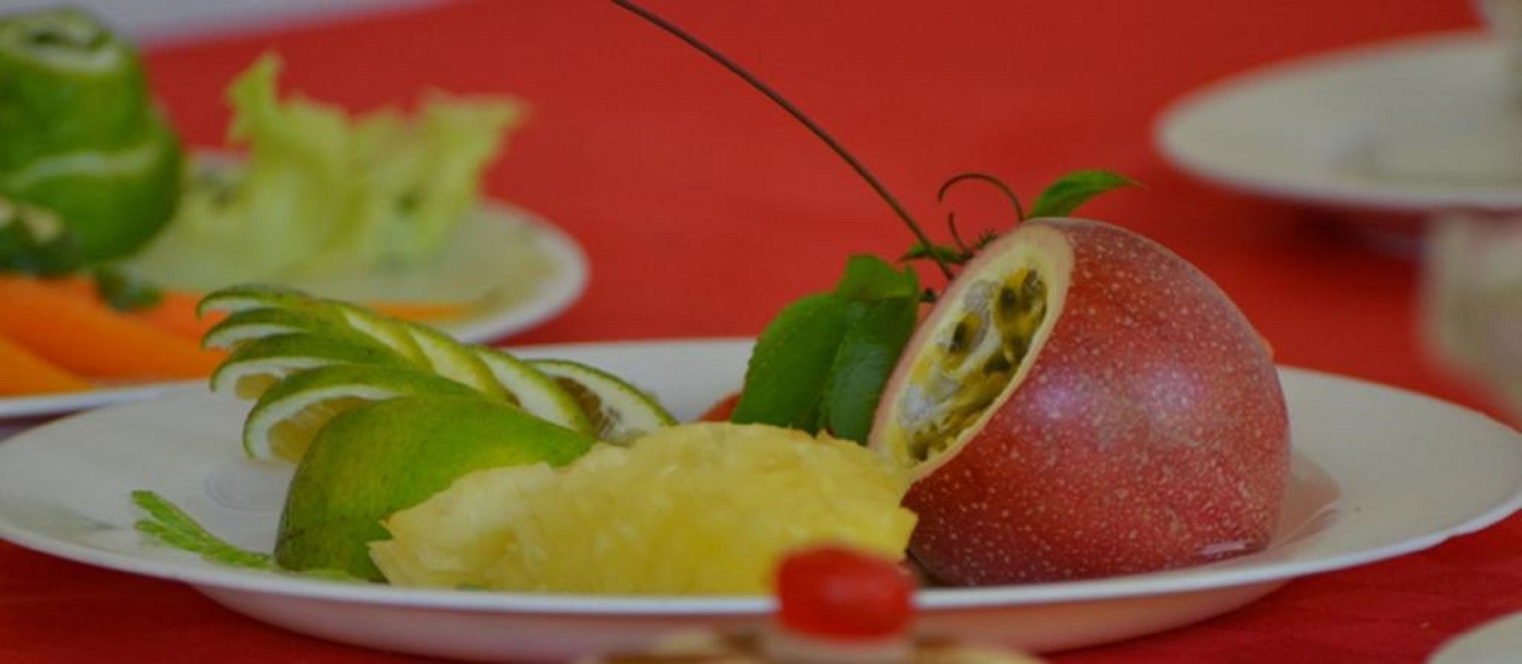 A plate with a red fruit, possibly a guava, and slices of lime and pineapple.