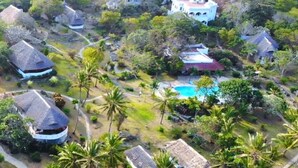A resort with multiple buildings, a swimming pool, and palm trees.