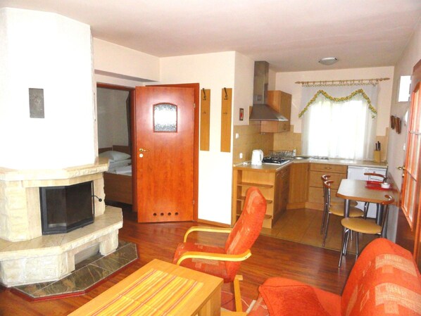 Un espacio habitable compacto con chimenea, comedor y kitchenette.