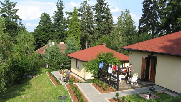 A residential area with a house featuring a red roof, a small garden with young trees, and a paved driveway. - Ośrodek Wypoczynkowy Bajka 3 (Lagow)