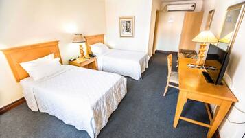 A hotel room with two beds, a desk with a computer, a chair, and a TV.