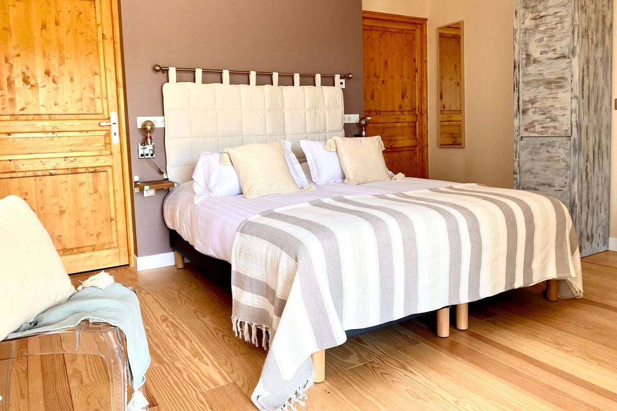 Un dormitorio con cama, armario de madera y una silla.
