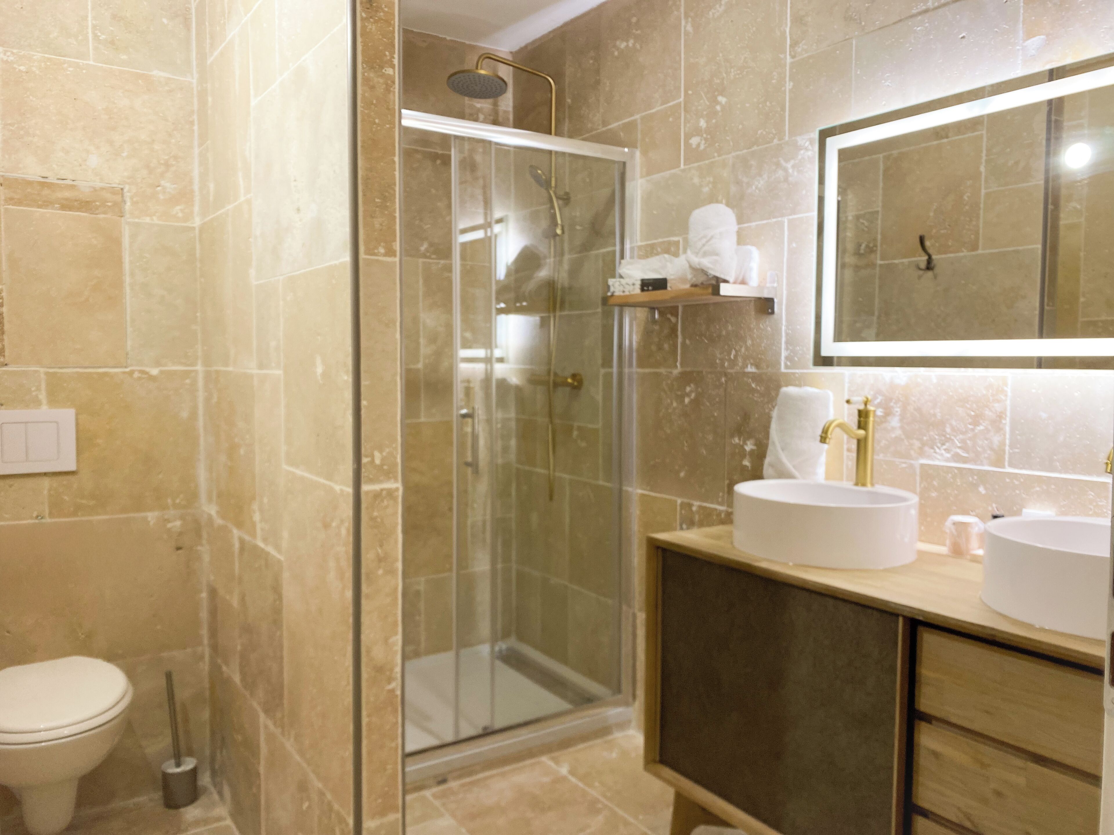 Ein Badezimmer mit Duschkabine, Toilette und Waschtisch mit Waschbecken und Spiegel.