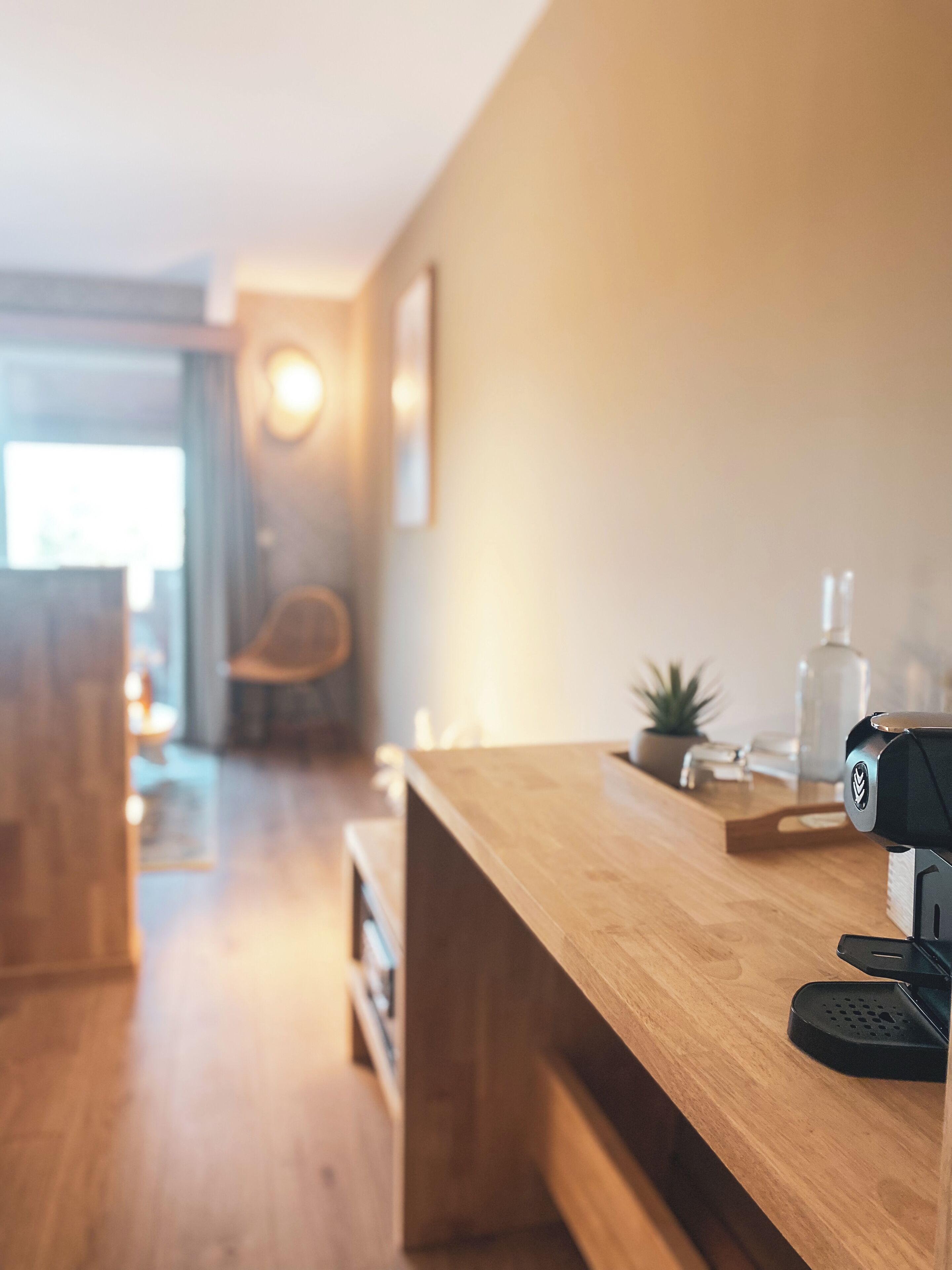 Une cuisine moderne avec des plans de travail en bois, une machine à café et une petite plante.