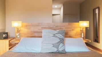 Habitación de hotel con una cama, dos lámparas de noche, una mesita de noche y un cabecero de madera.
