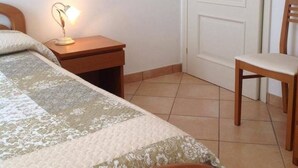 Une chambre à coucher avec un lit, une table de chevet, une lampe, une chaise et une porte.