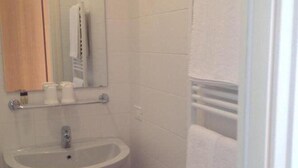 Une petite salle de bain avec un lavabo, un miroir et un porte-serviettes.